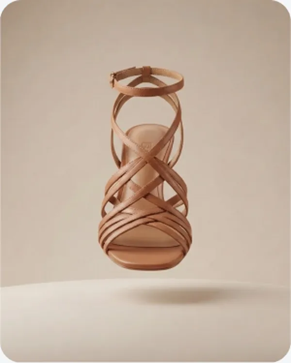 Tan strappy heel floating on a plain ground